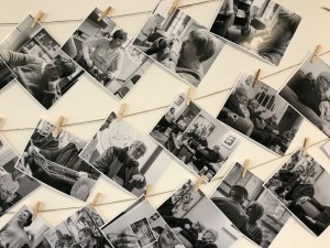 A stylized image of strings with black-and-white photos clipped to them in rows. The photos are candid shots of individuals and groups smiling, chatting, hugging, and spending time together.