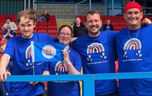 A group photo of four smiling people wearing Borders Recovery Group T-shirts